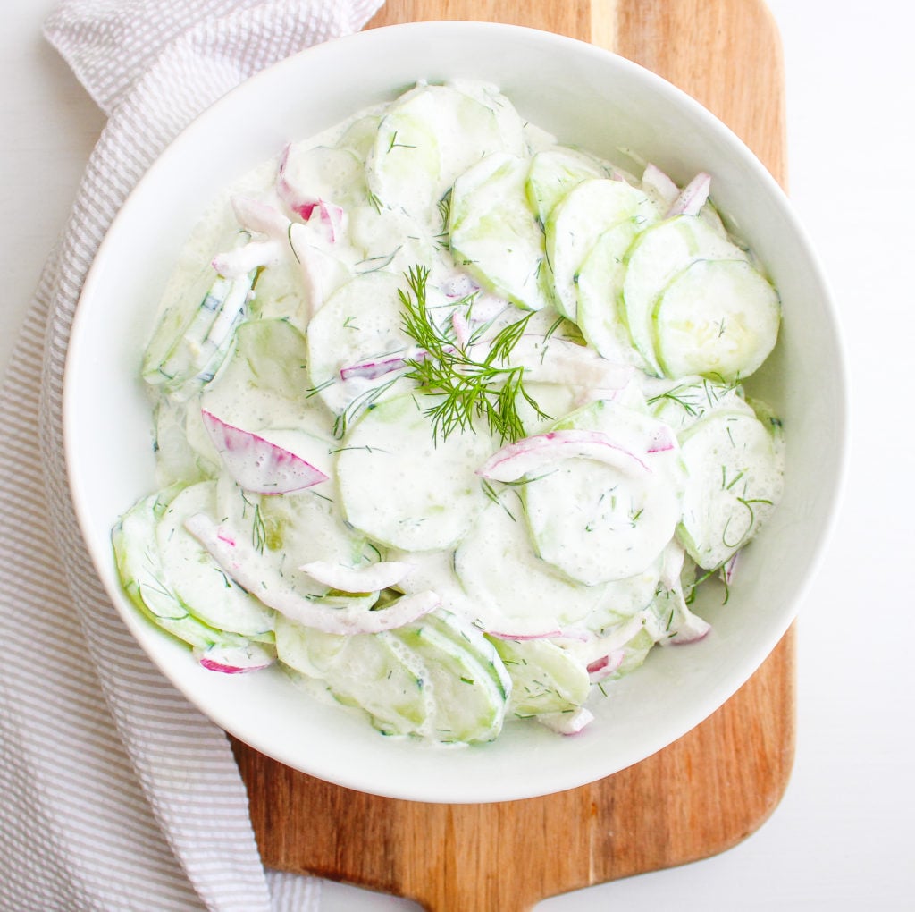 Bowl of polish cucumber salad topped with fresh dill 