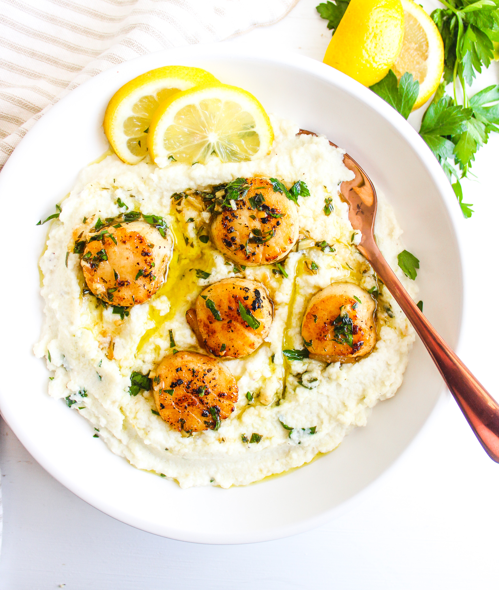 Seared Scallops in Lemon Garlic Sauce over creamy cauliflower mash with fresh sliced lemons on the side