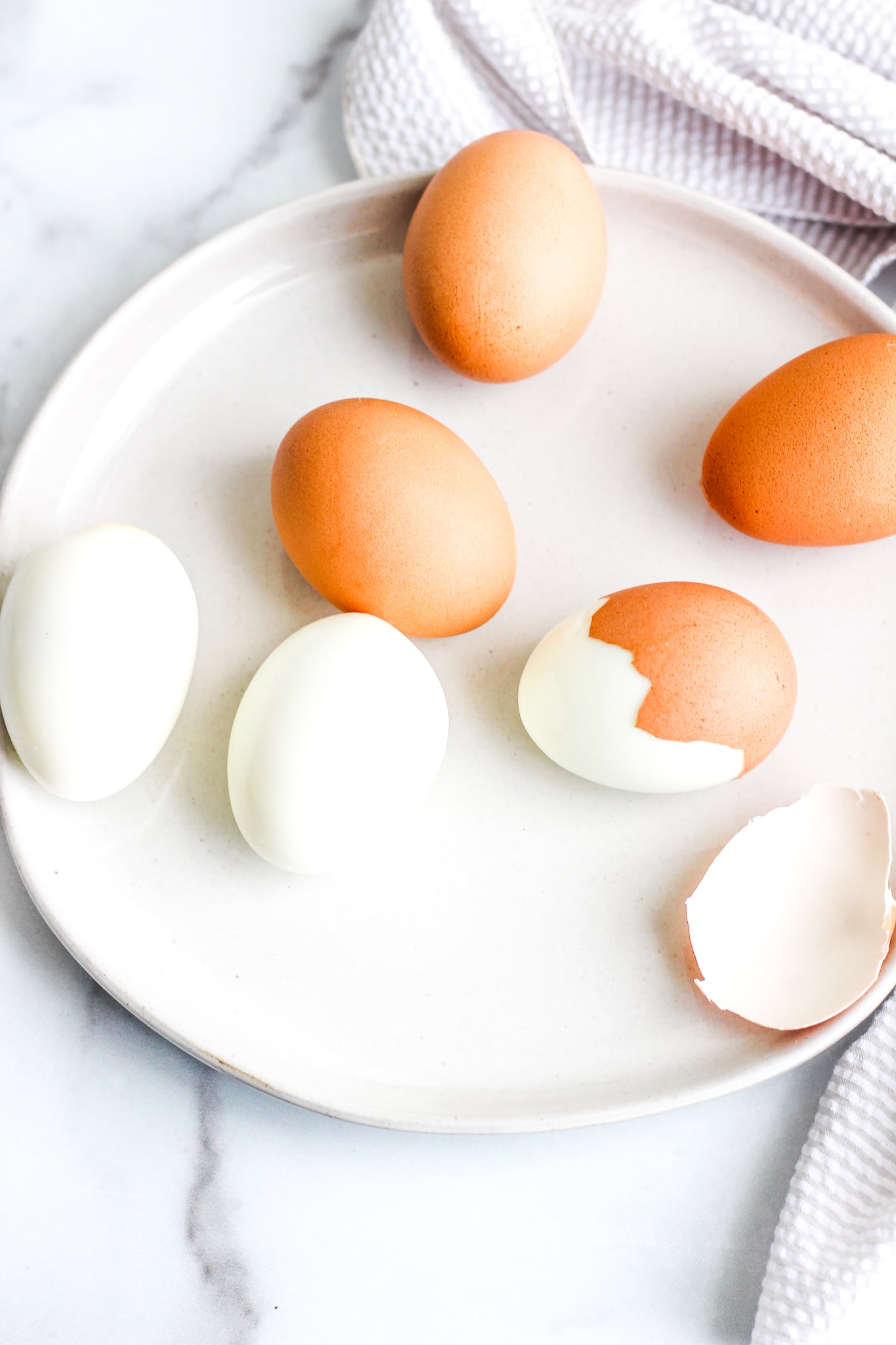 peeled Instant Pot hard boiled eggs on a ceramic plate with shells cracked around 
