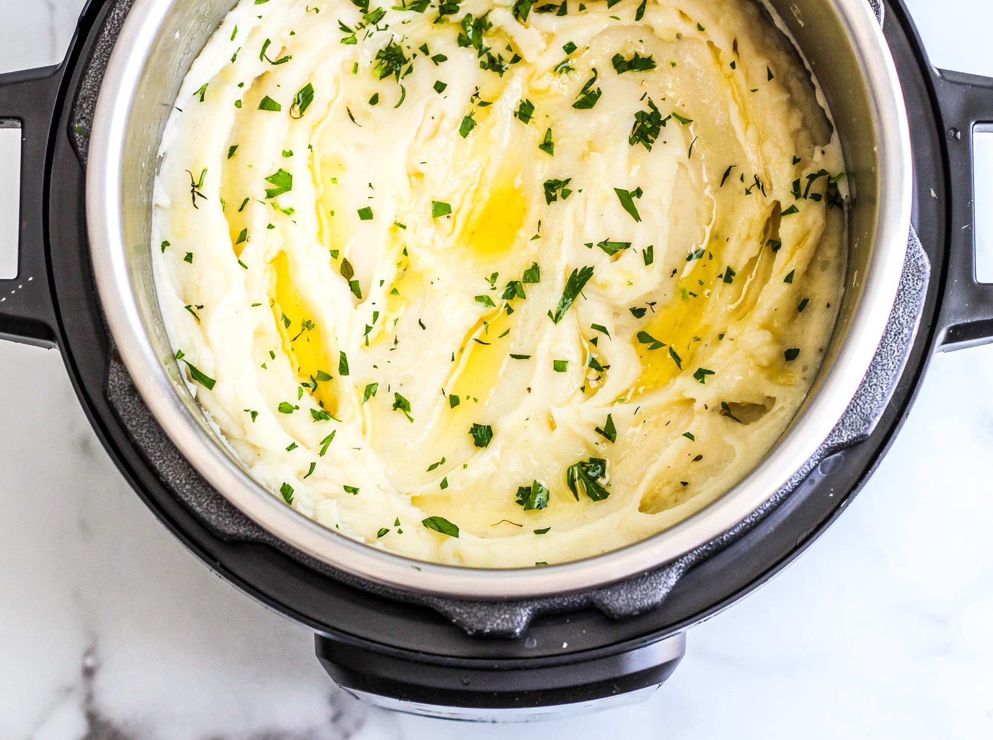 Creamy mashed potatoes in the Instant Pot top with ghee and fresh parsley 