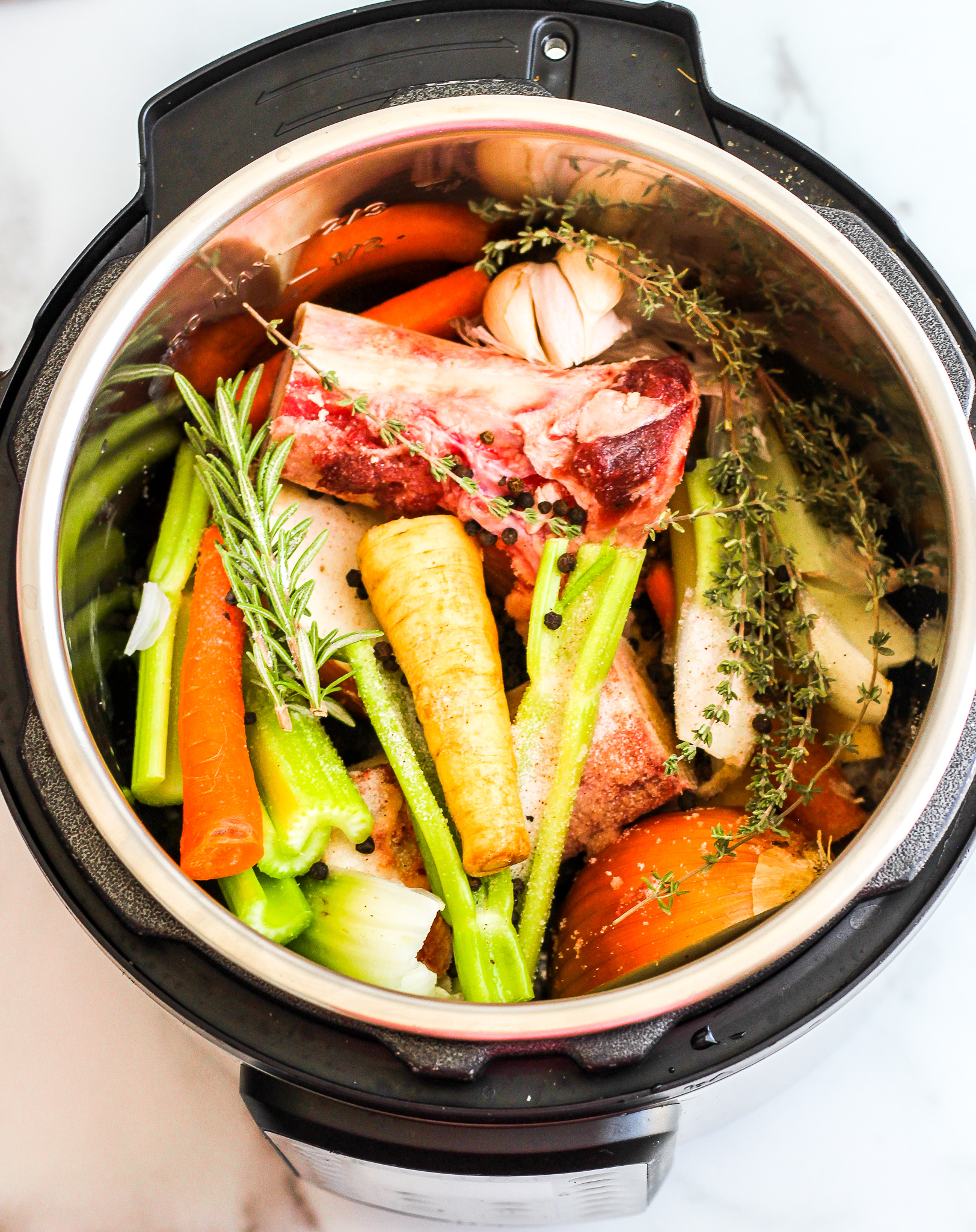 Instant Pot filled with veggies, herbs and beef bones for bone broth