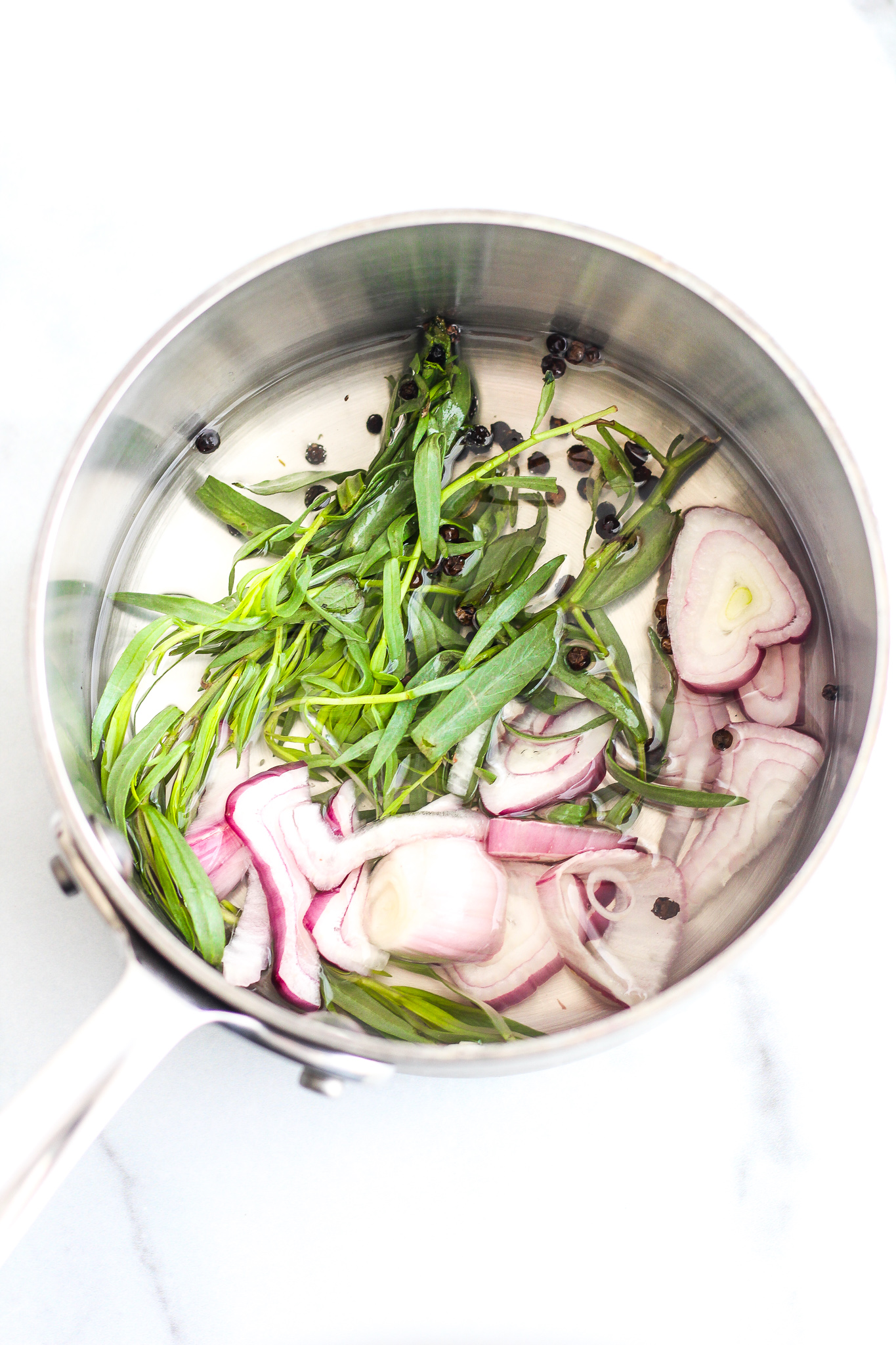 stainless steel saucepan with white wine vinegar, chopped shallots, whole black peppercorns and fresh tarragon 