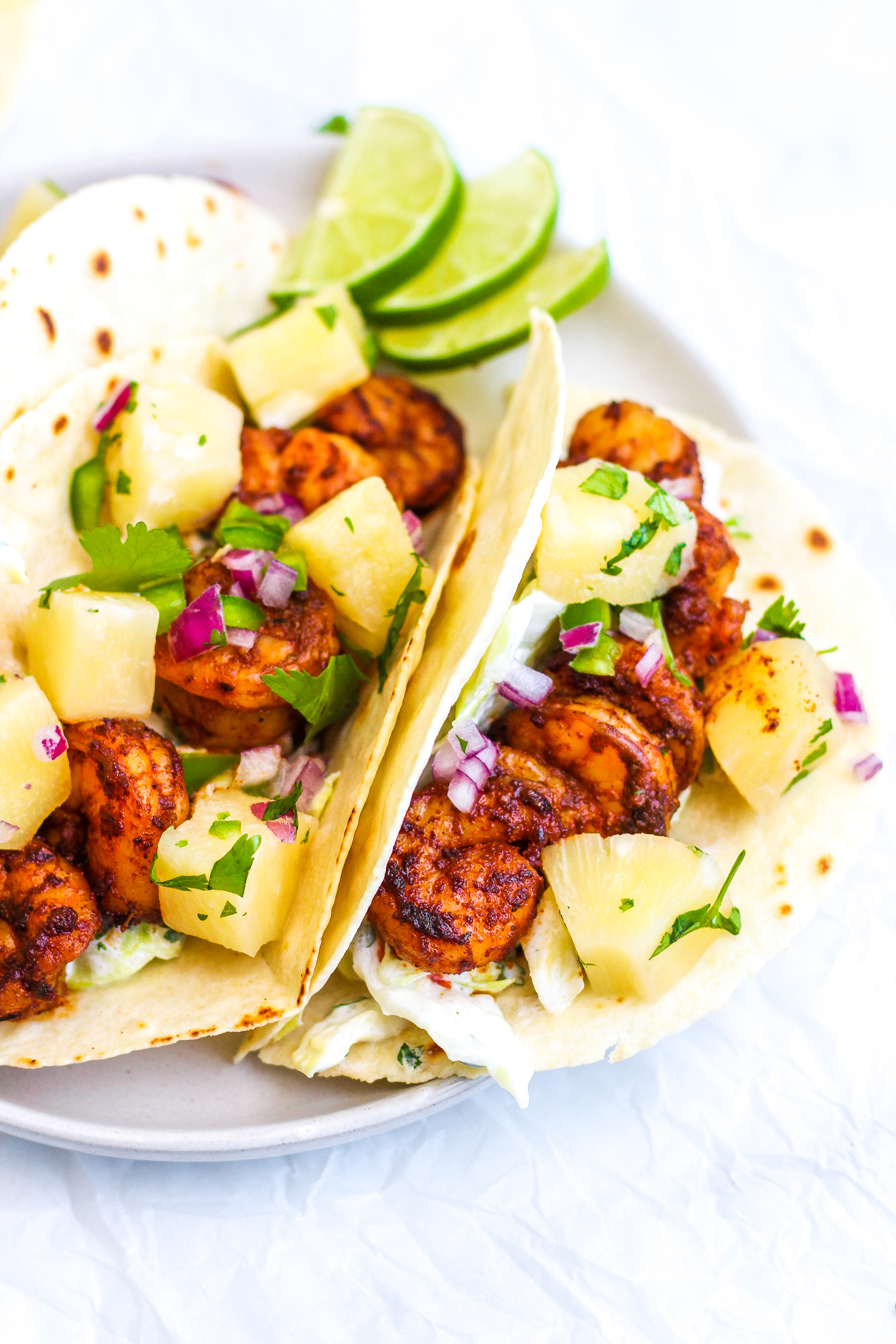Side angle of three grain free tortillas filled with creamy cabbage slaw, spiced shrimp and pineapple salsa 