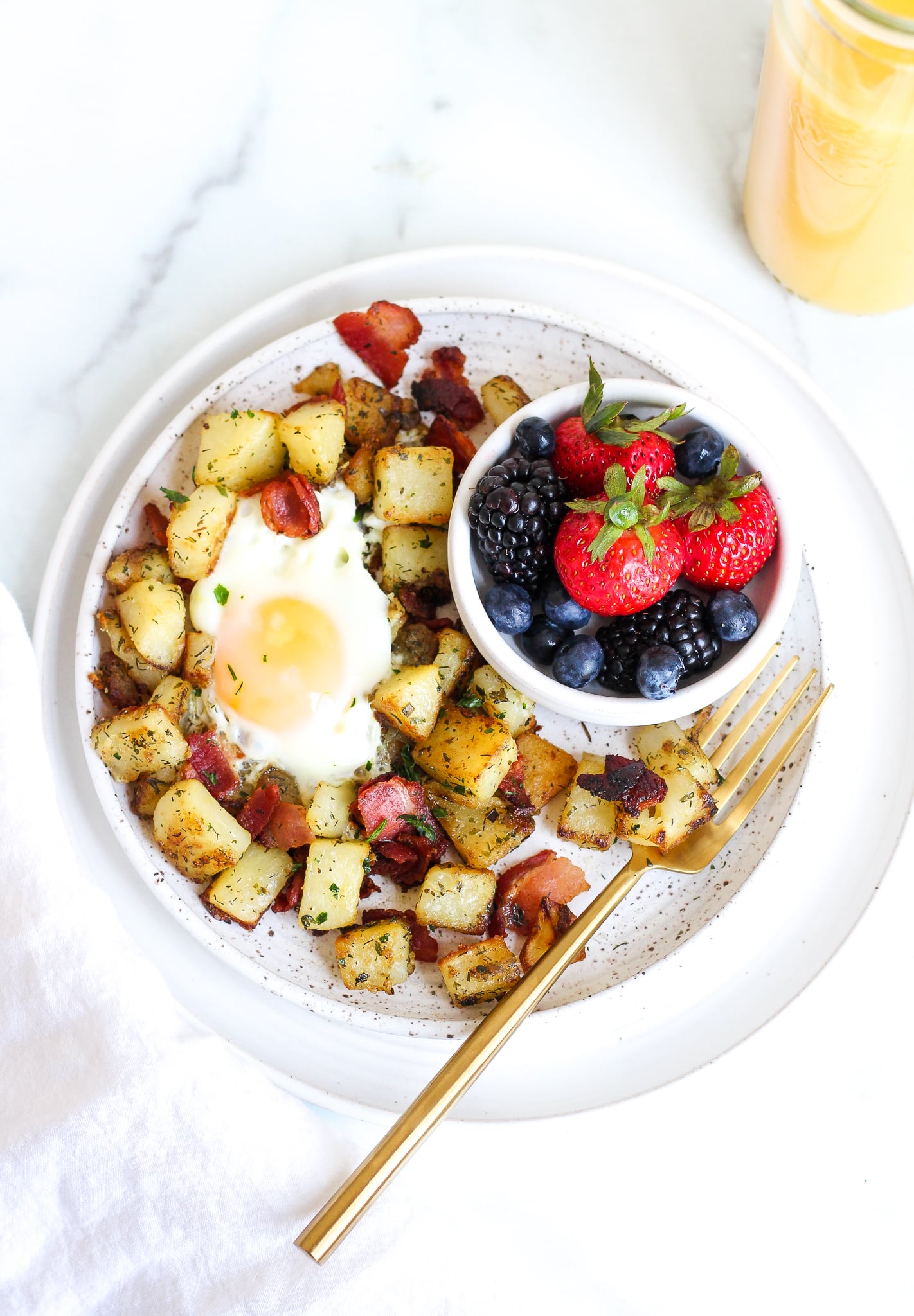 bacon breakfast skillet with ranch home fries on a ceramic plate with a side of fresh berries 