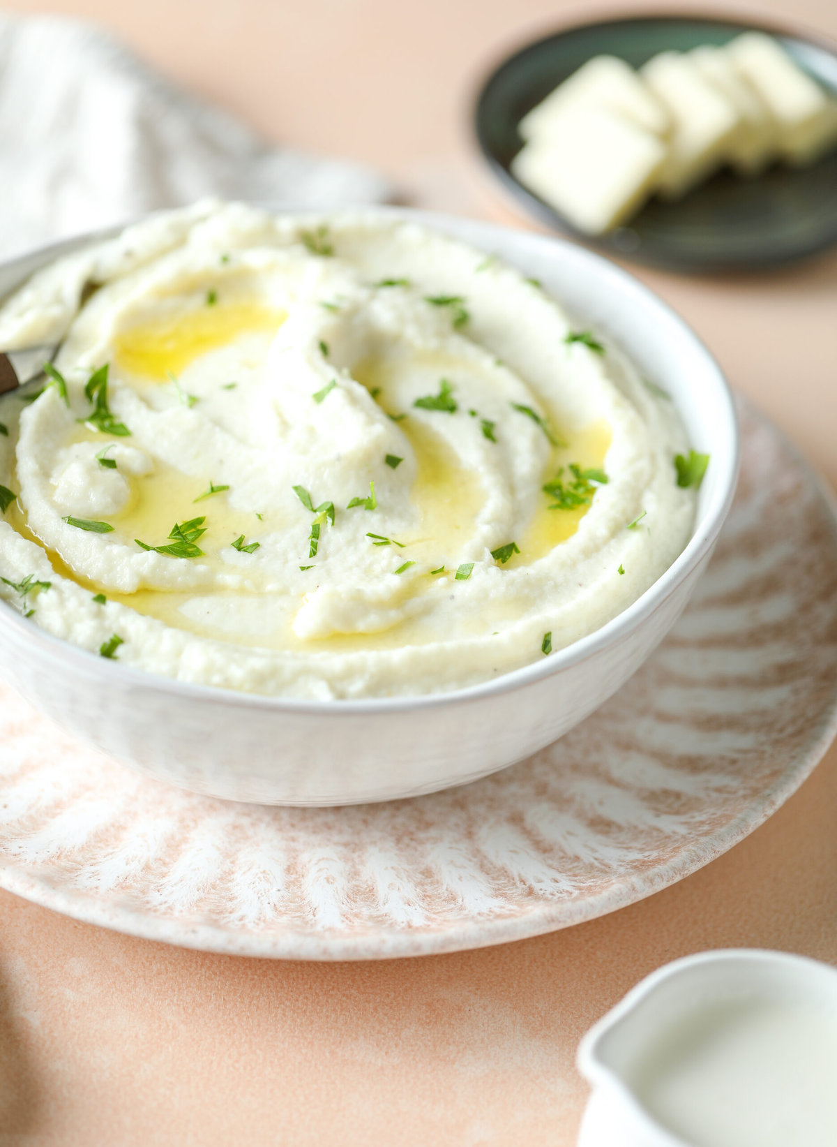 Creamy cauliflower mash piled in a serving bowl and topped with swirls of melted butter
