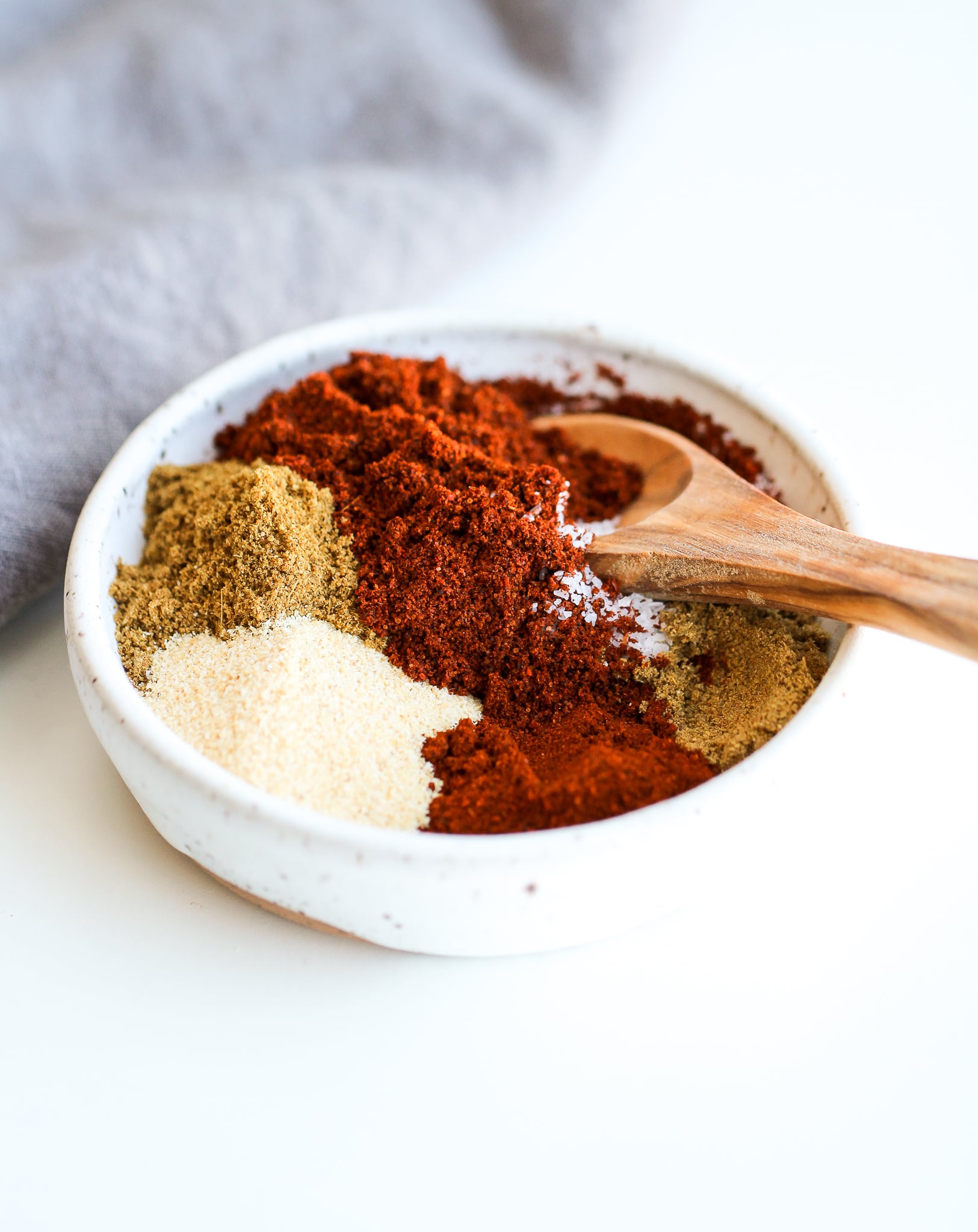 Spice mixture for instant pot fajita steak in a small white spice bowl with a small wooden spice spoon in it 