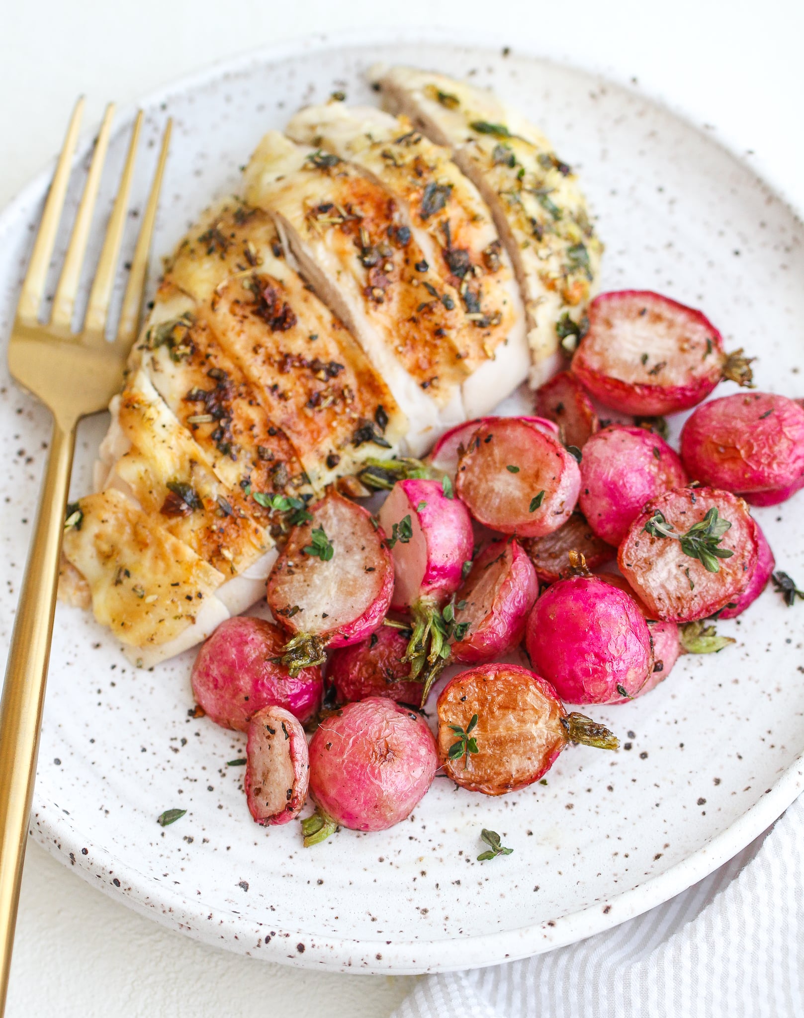 roasted radishes served alongside sliced herb roasted chicken breast