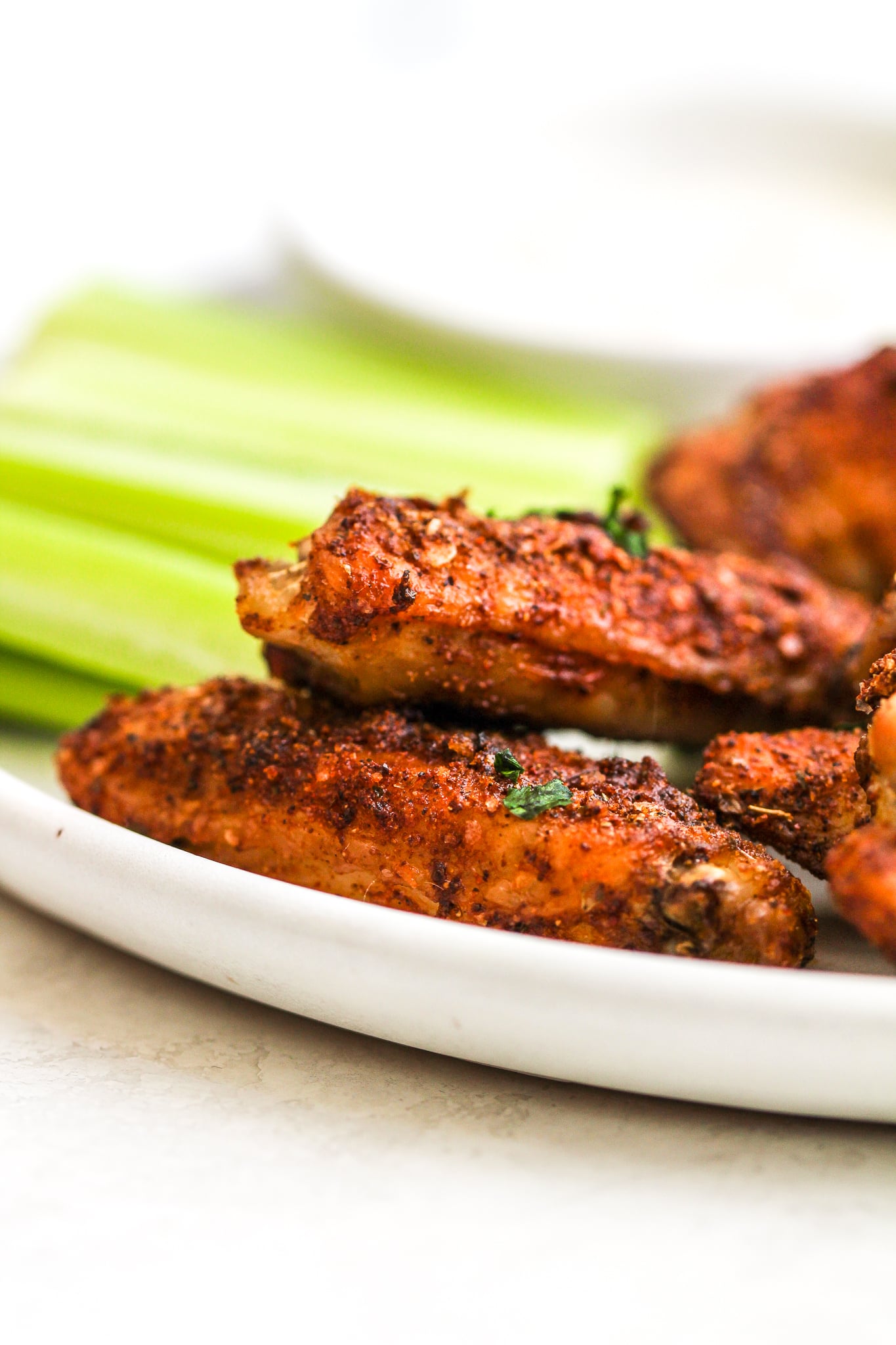 up close photo of crispy dry rub chicken wings on a white plate 