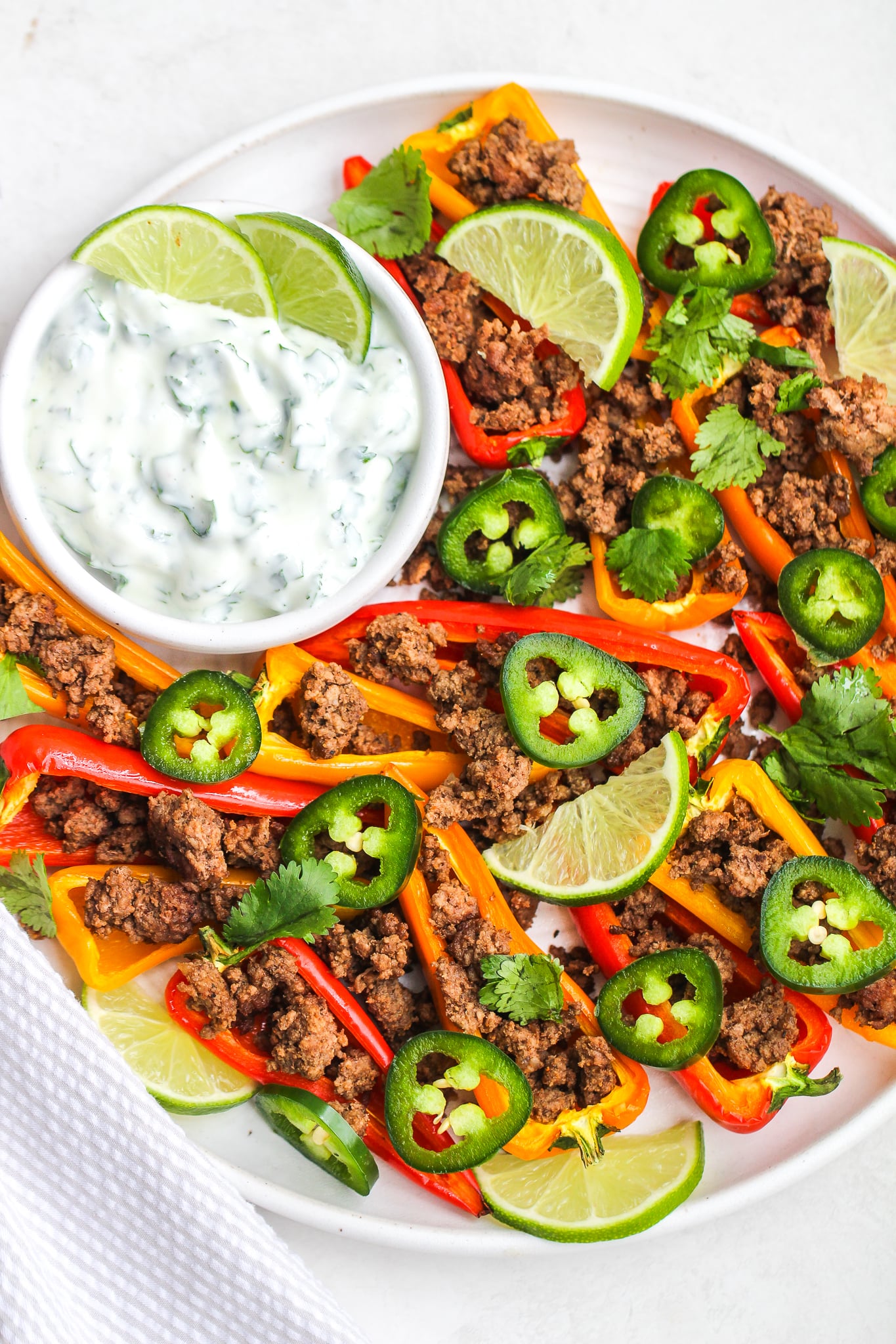 sweet pepper nachos topped with ground beef, sliced jalapeños, lime wedges, and cilantro served with a side of cilantro lime greek yogurt sauce