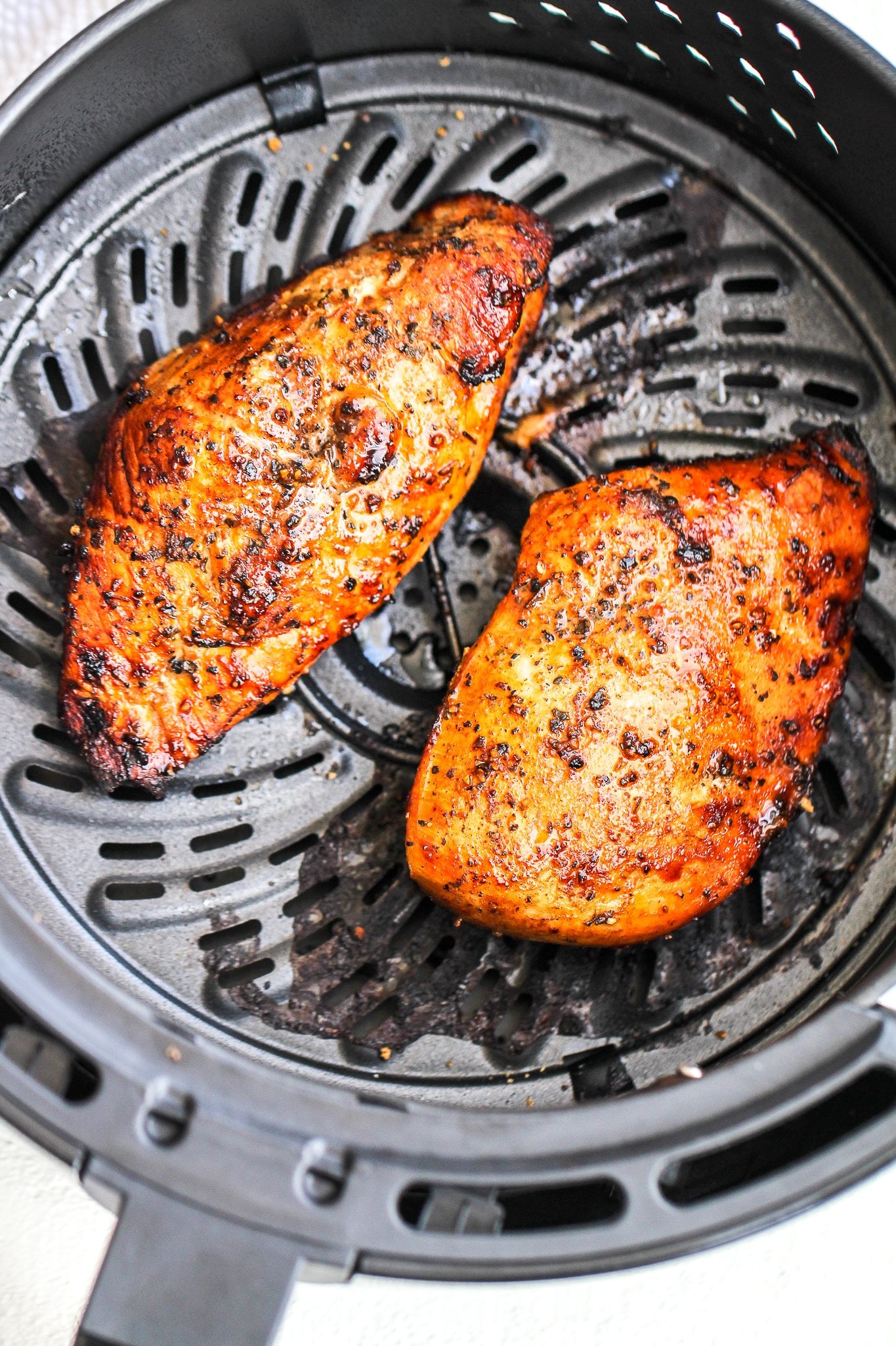 cooked chicken breasts in the air fryer basket 