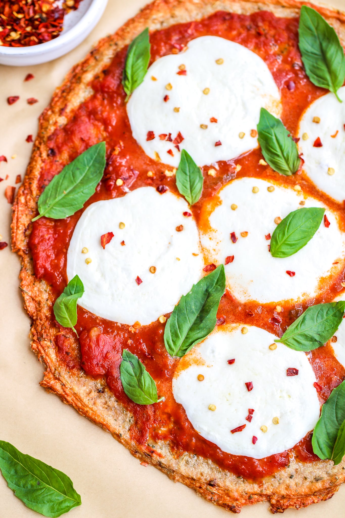 close up of low carb ground chicken pizza crust topped with marinara, fresh mozzarella and fresh basil