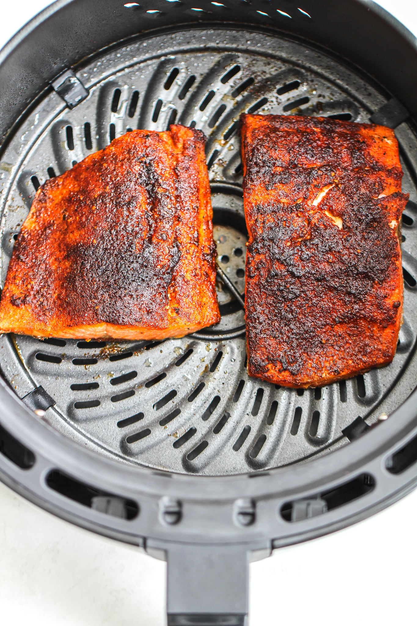 Cooked air fryer blackened salmon in an air fryer basket 