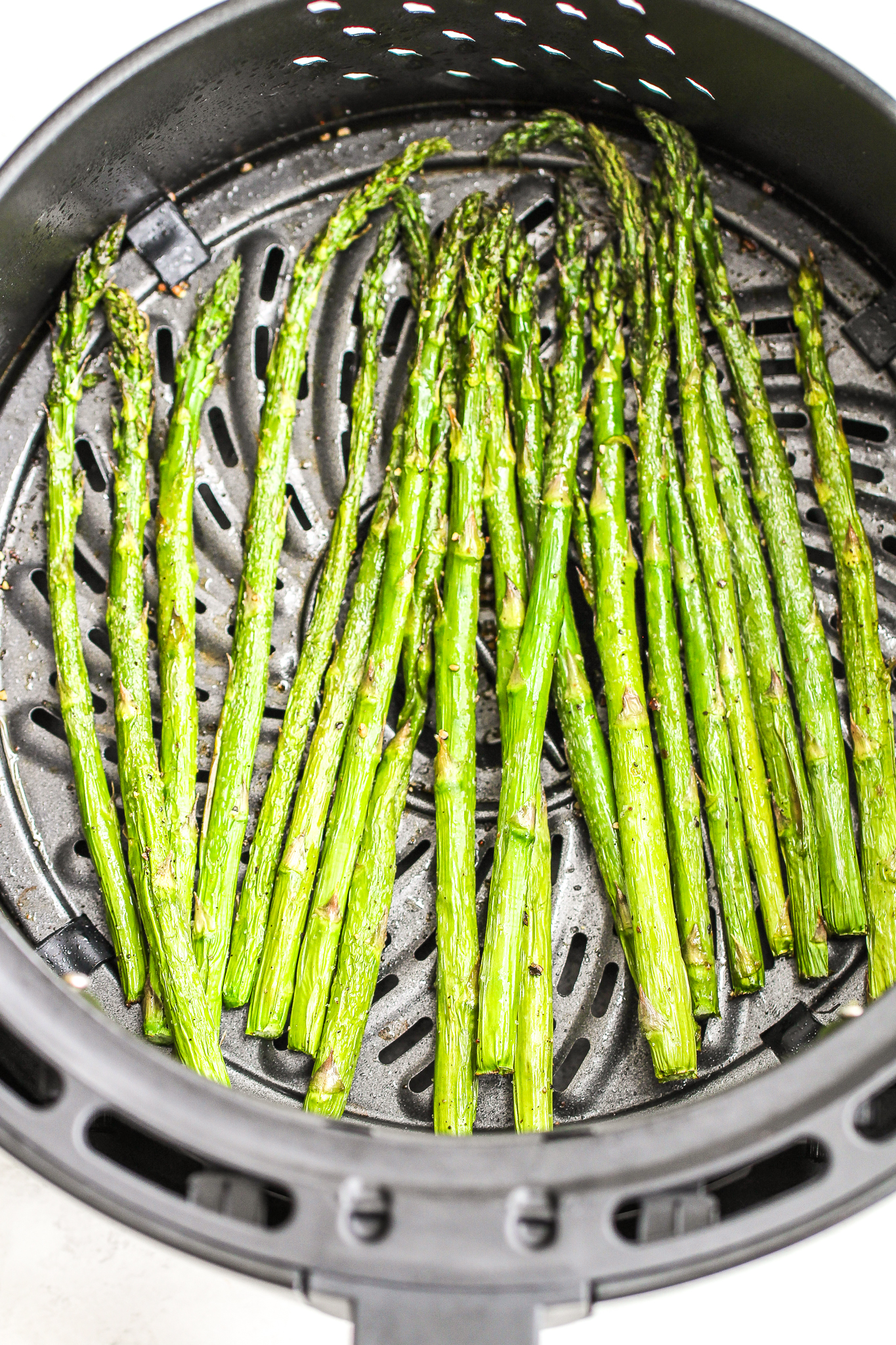 asparagus in an air fryer basket tossed with cooking spray and salt & pepper 