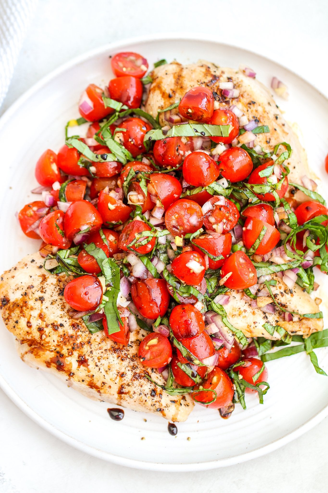bruschetta chicken on a ceramic platter drizzled with balsamic glaze 