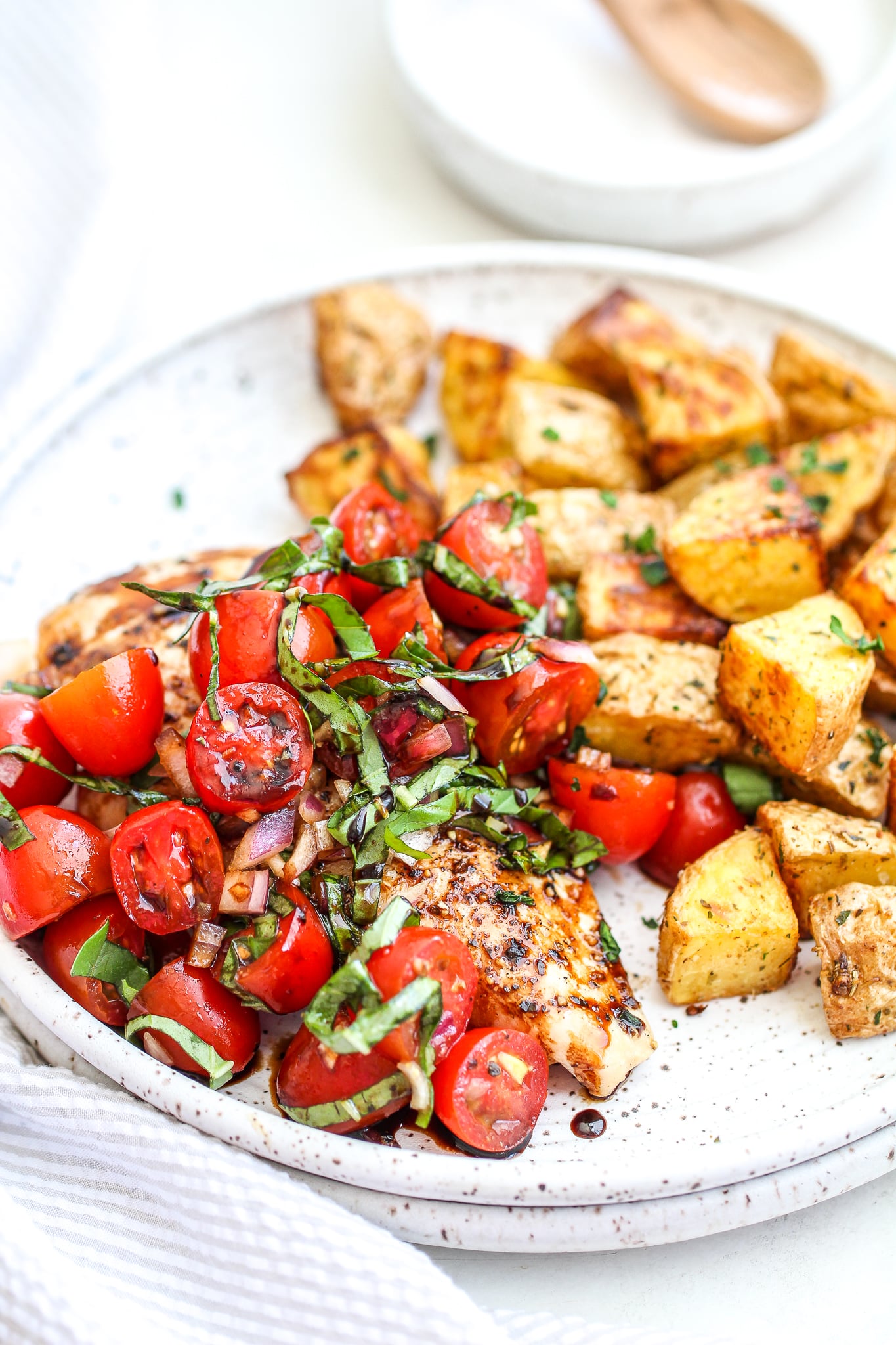 bruschetta chicken on a ceramic plate with a side of herb roasted potatoes 