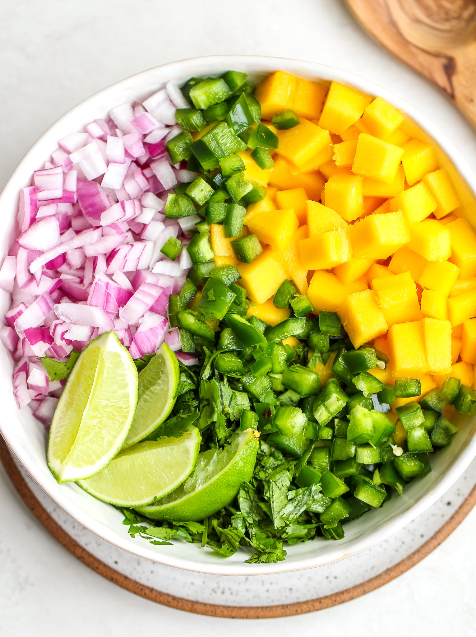 ingredients separated for mango salsa in a white serving bowl 