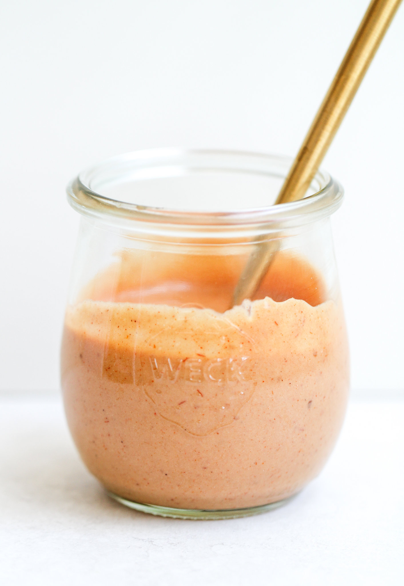 side view of the paleo fry sauce in a clear storage jar - it has a gold spoon sticking out of it 