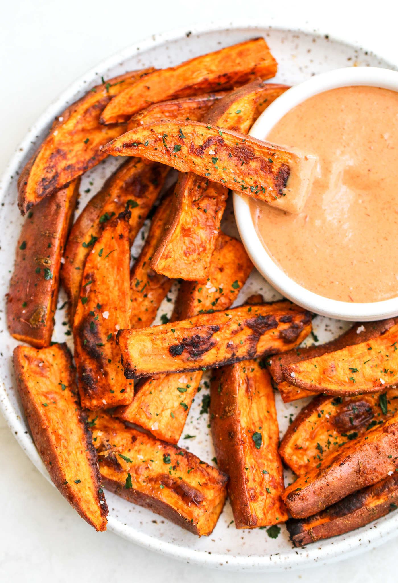 plate of sweet potato wedges and one of the wedges is in the paleo fry sauce 