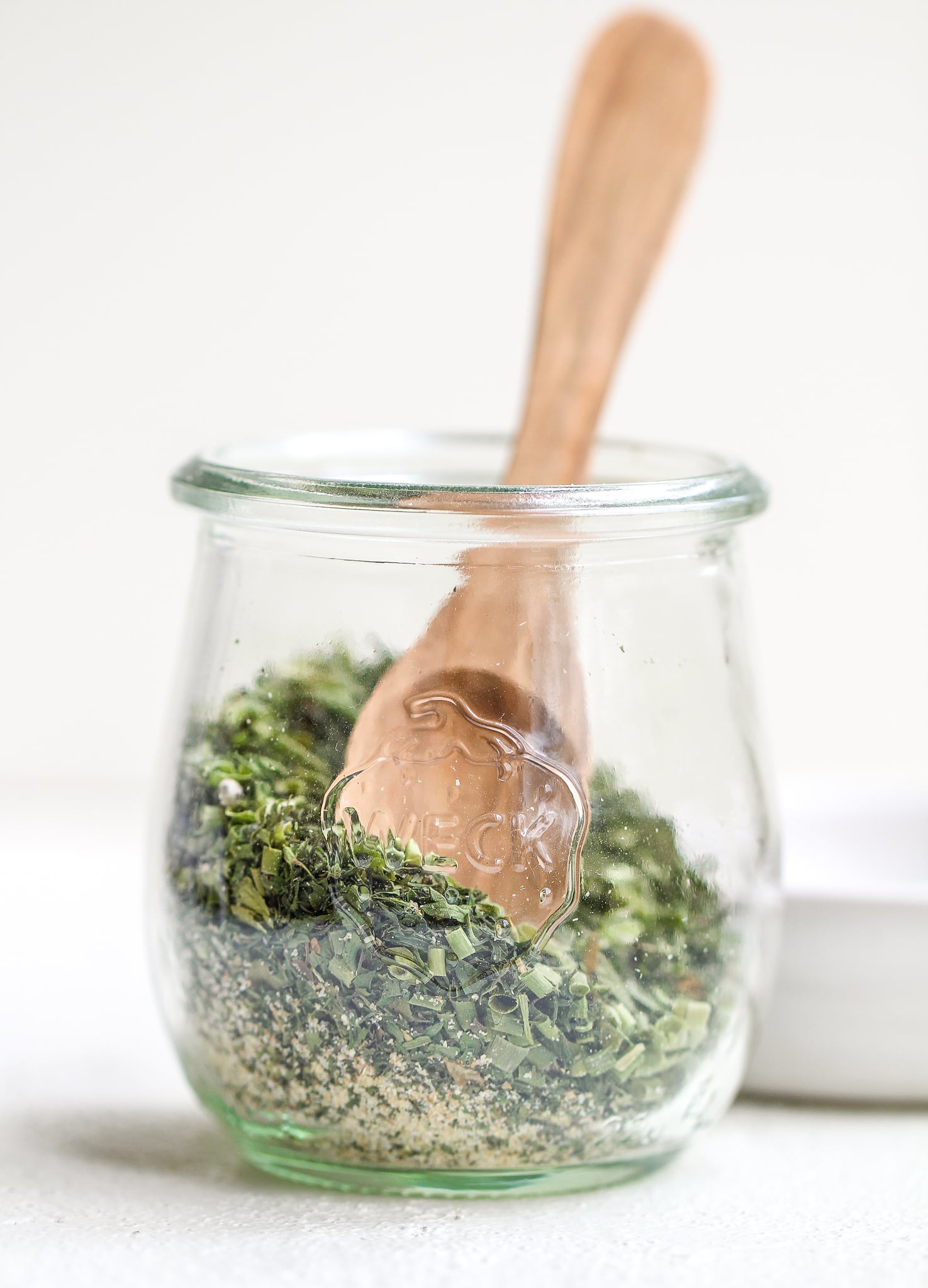 healthy homemade ranch seasoning in a clear glass weck jar with a wooden spoon in it 