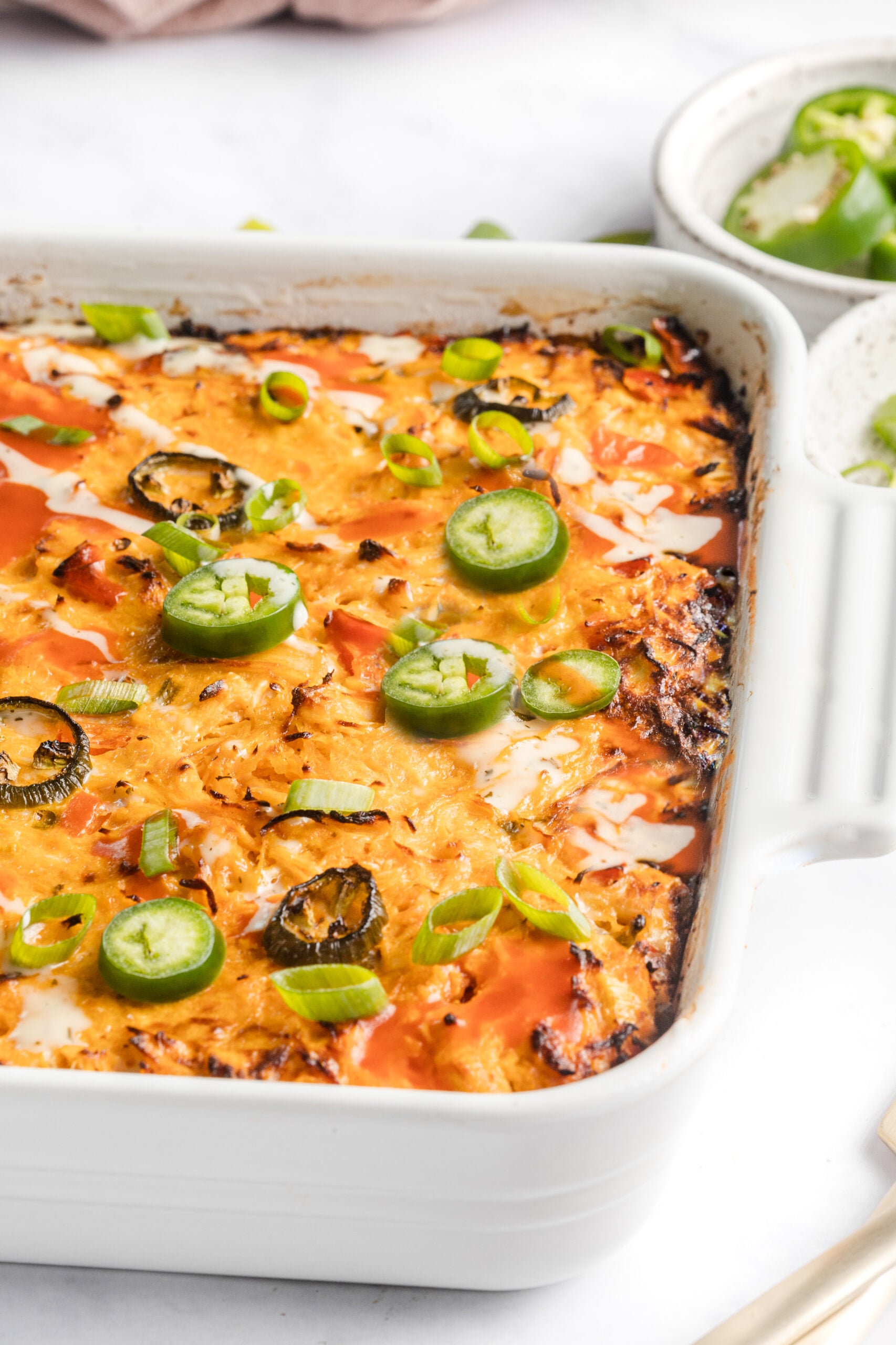 healthy buffalo chicken casserole in a square ceramic baking dish 