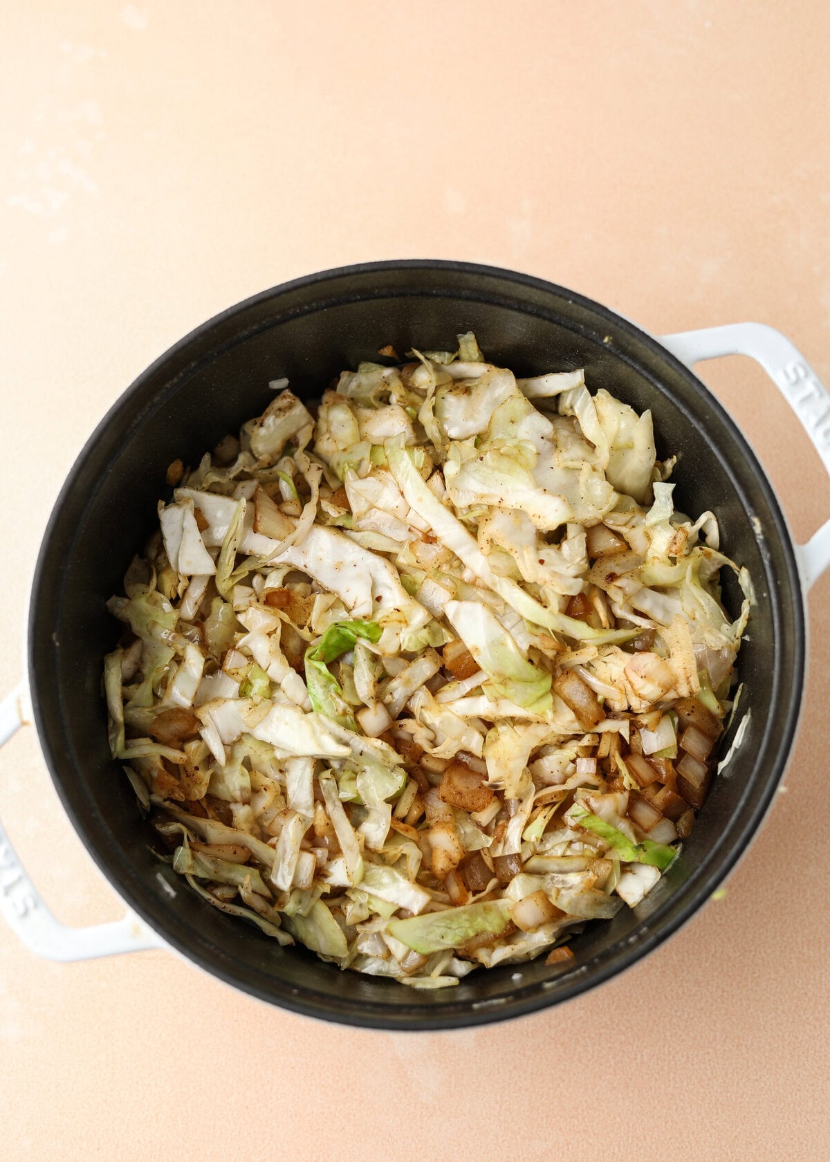 overhead shot of sautéed cabbage and onion in a white dutch oven