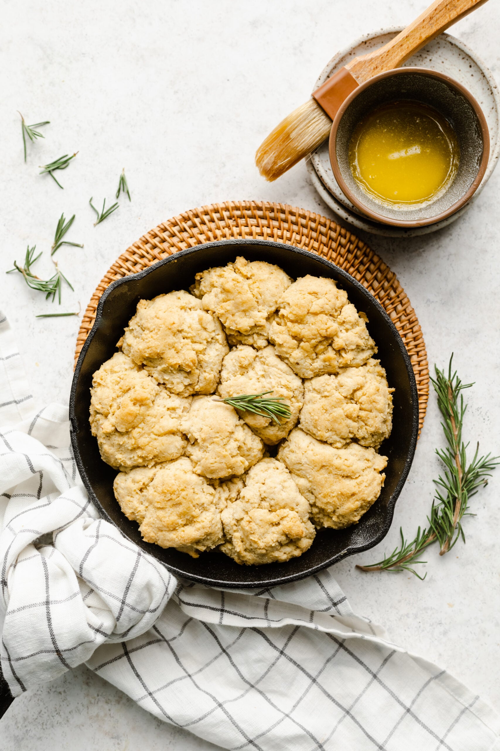 Gluten free drop biscuits in a cast iron skillet with melted butter on the side