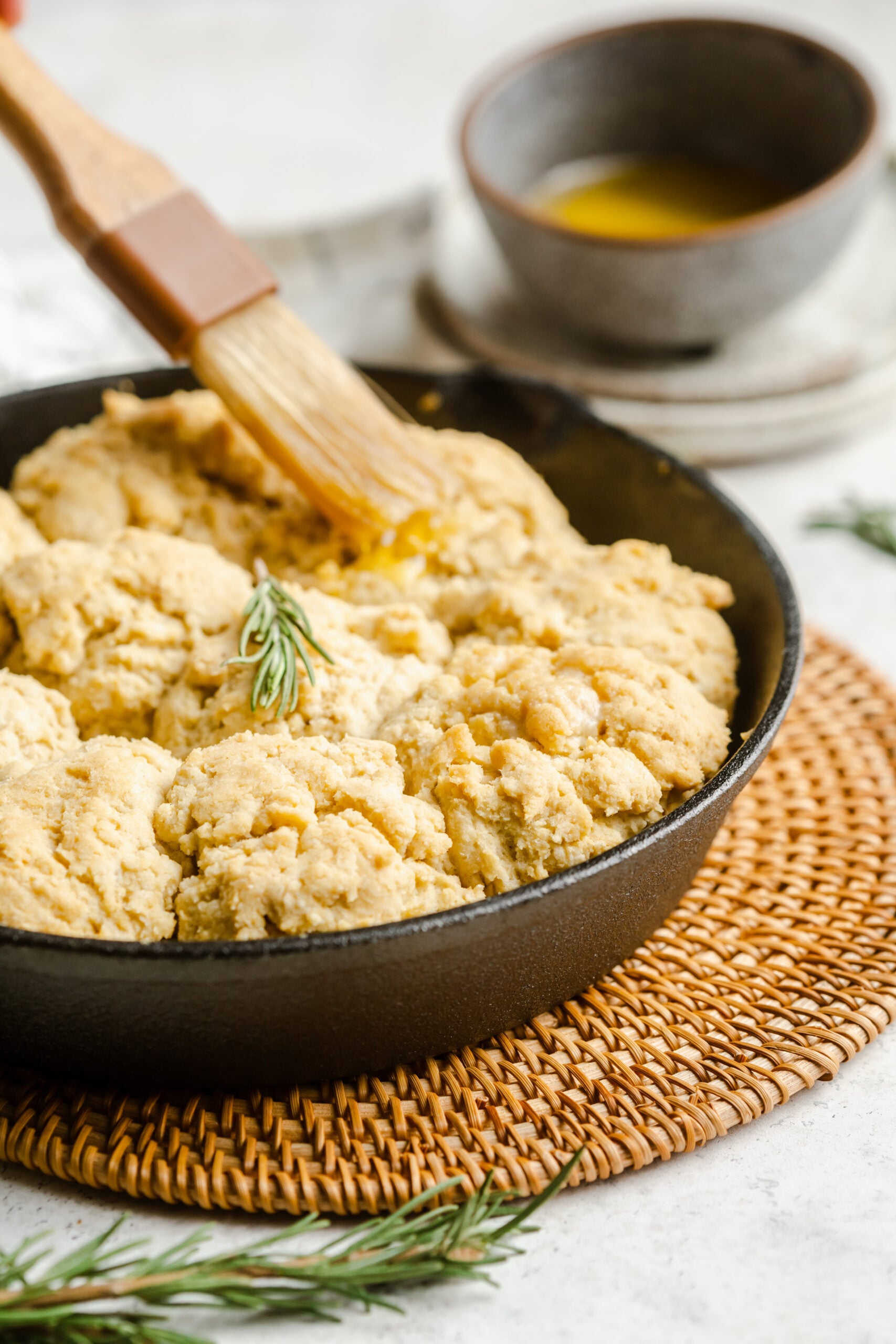 Basting brush shown putting brushing butter onto a pan of gluten free drop biscuits