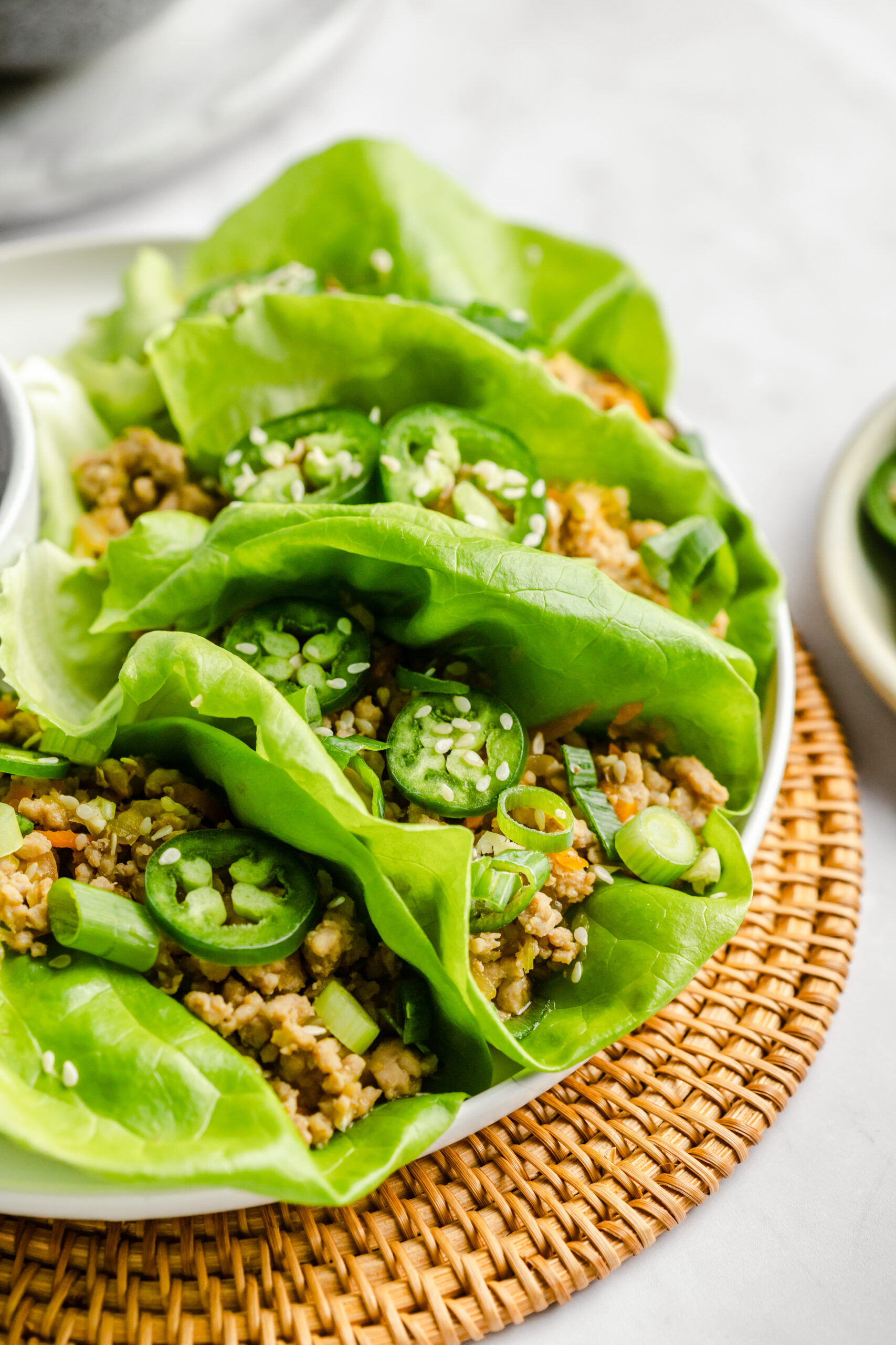 side view of spicy pork lettuce cups. they are topped with fresh jalapeño slices and sesame seeds