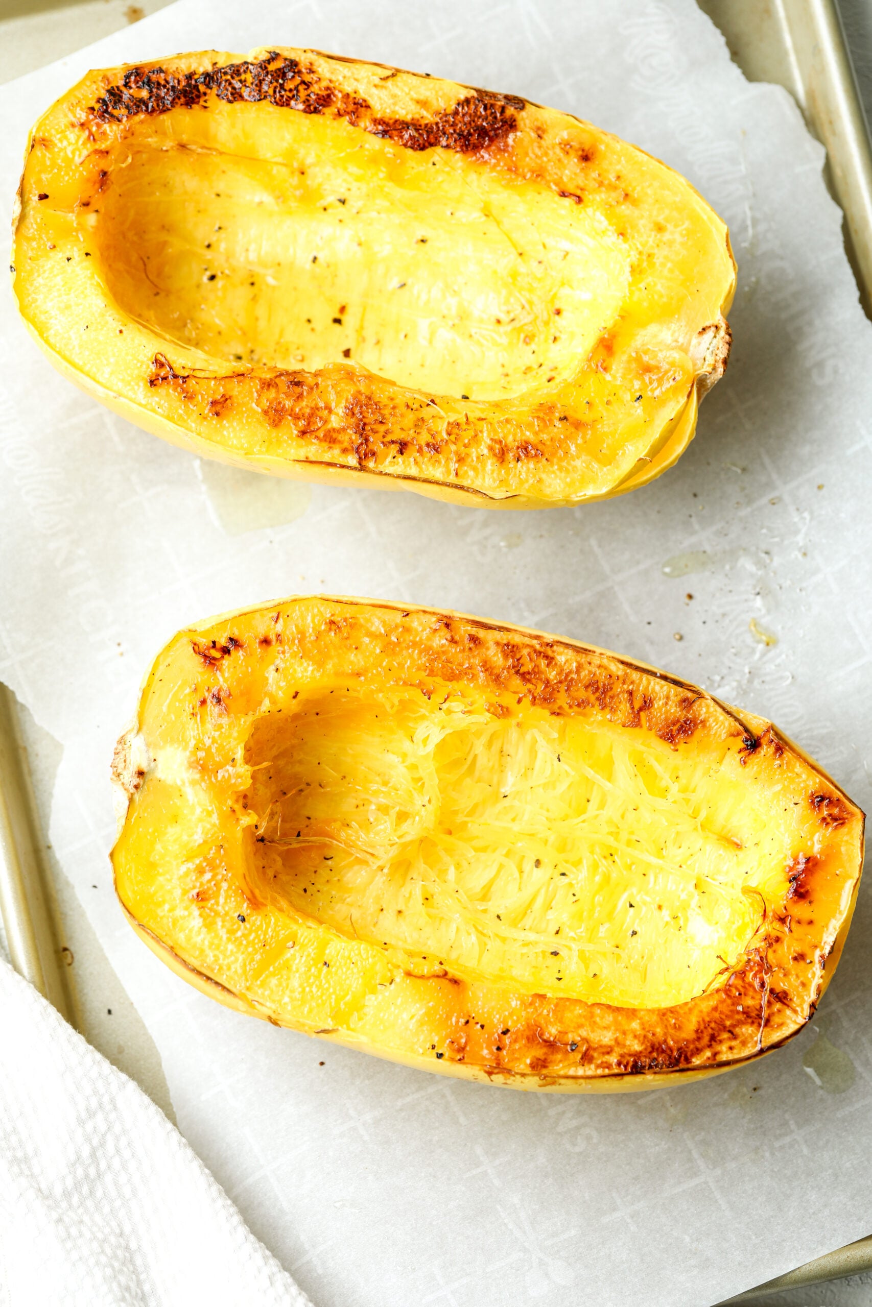 spaghetti squash that is sliced and roasted on a baking sheet 