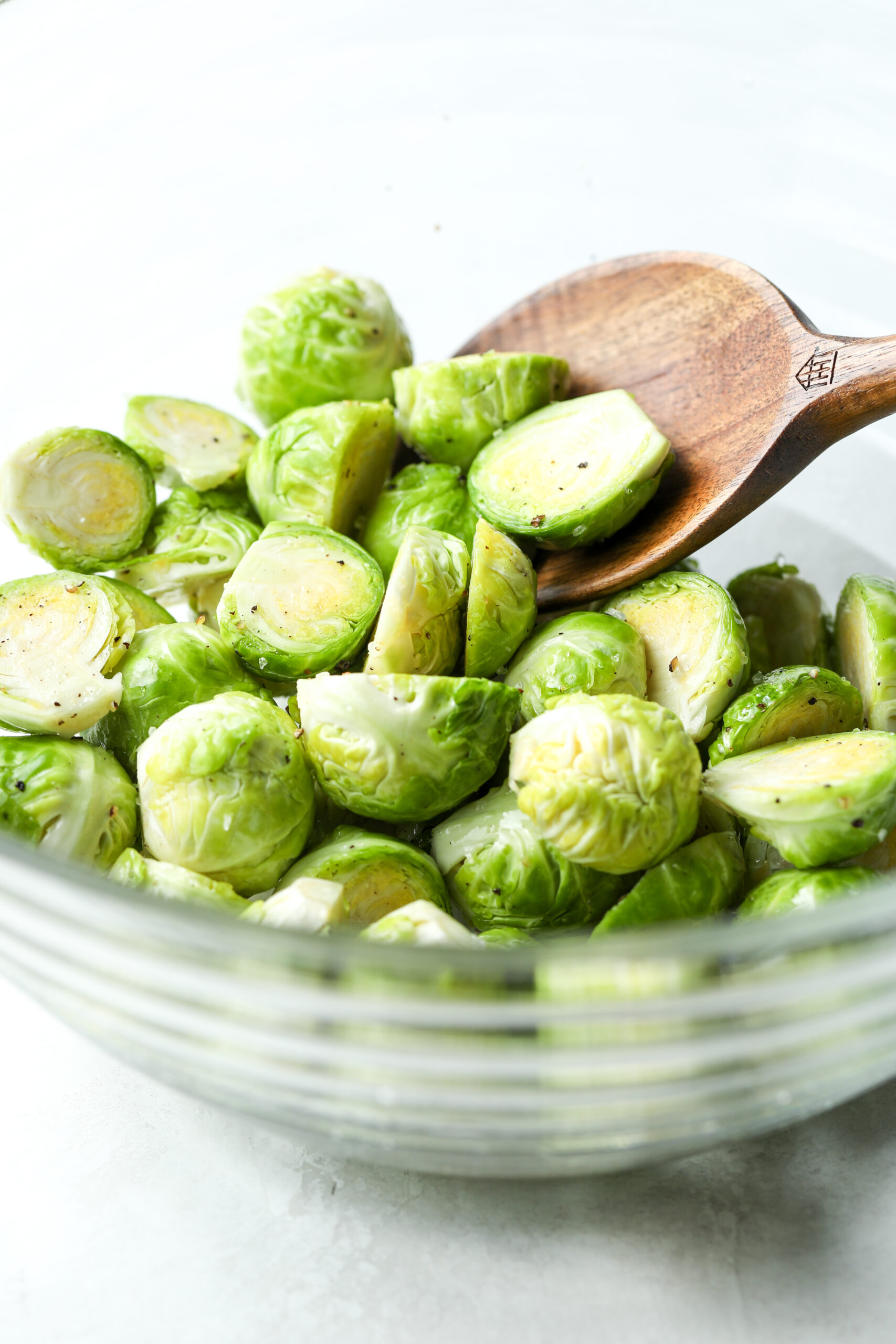 fresh Brussels sprouts in a glass bowl, they are tossed with olive oil and salt and pepper 