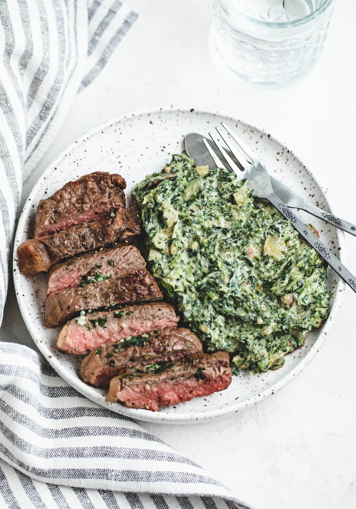 Creamed Spinach on a dinner plate, served alongside a steak.