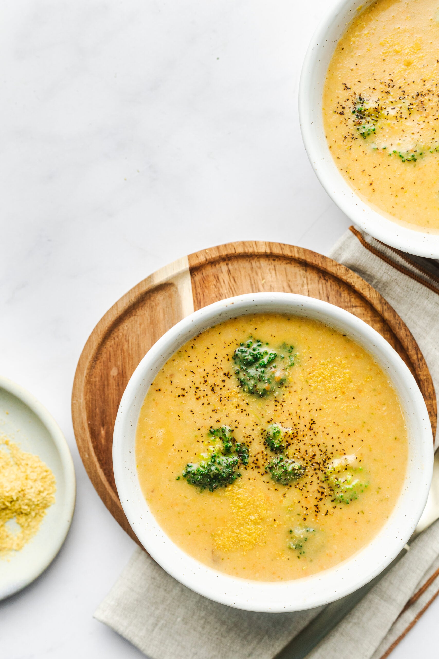 Overhead shot of two bowls of broccoli cheese soup. 