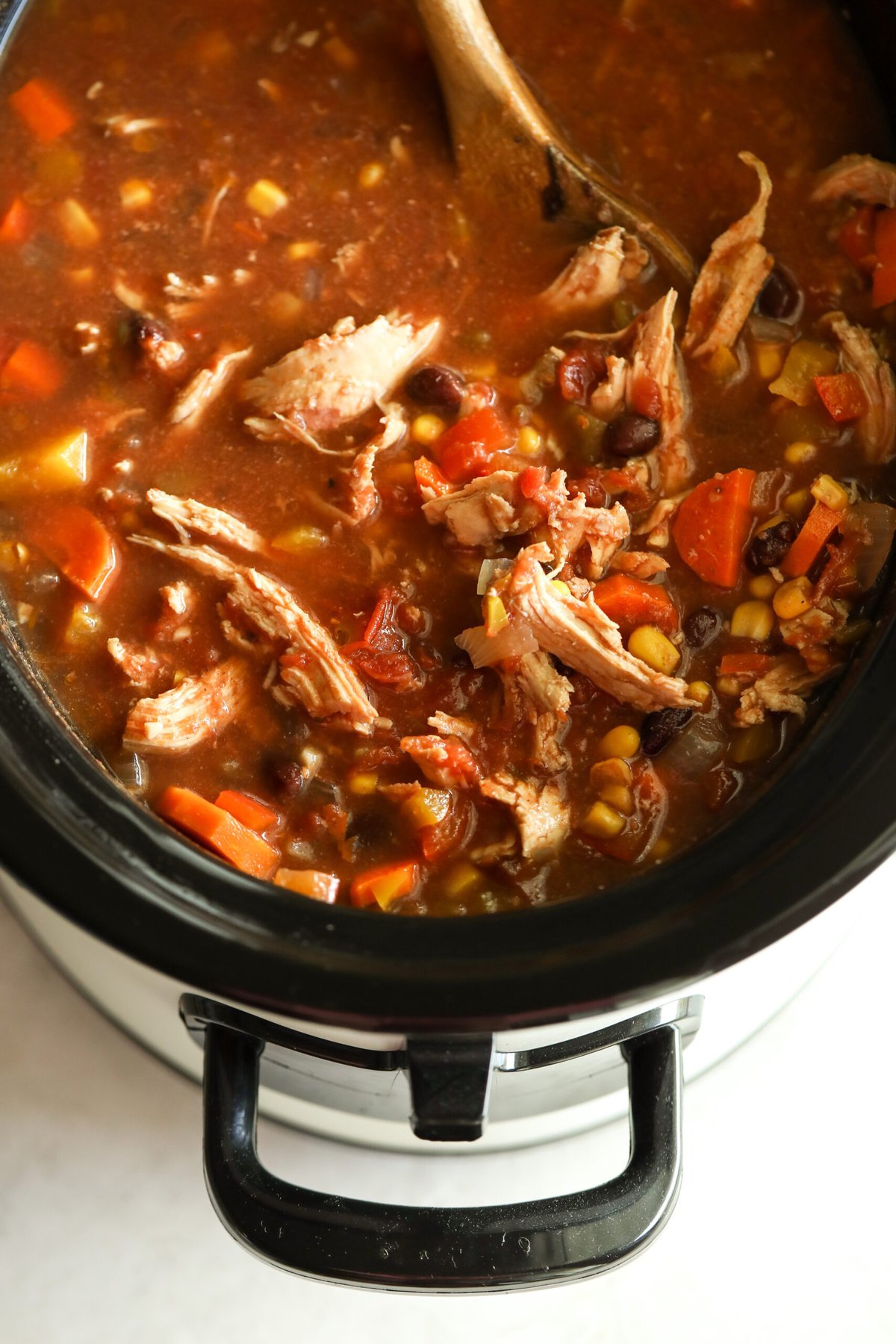 chicken taco soup in a slow cooker with a wooden spoon in it