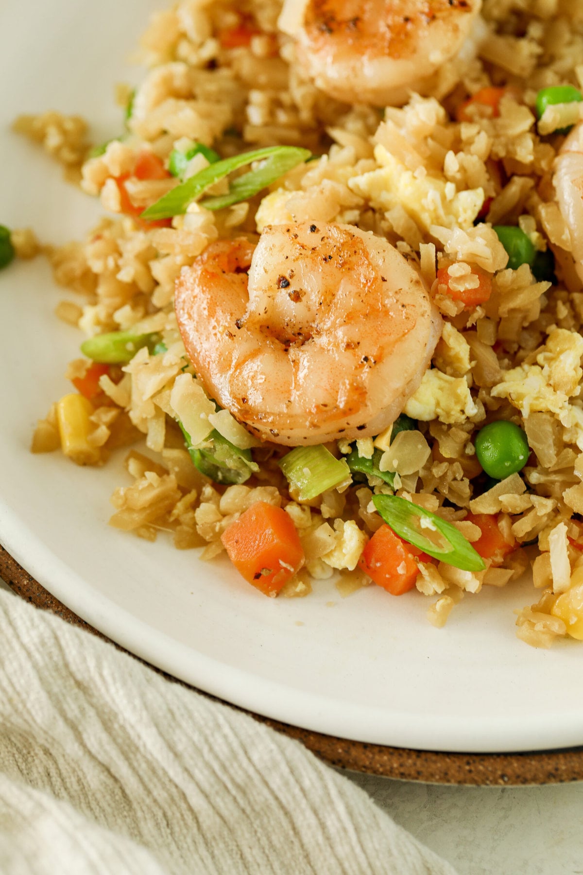 close up photo of a perfectly cooked shrimp sitting on a bed of cauliflower fried rice.