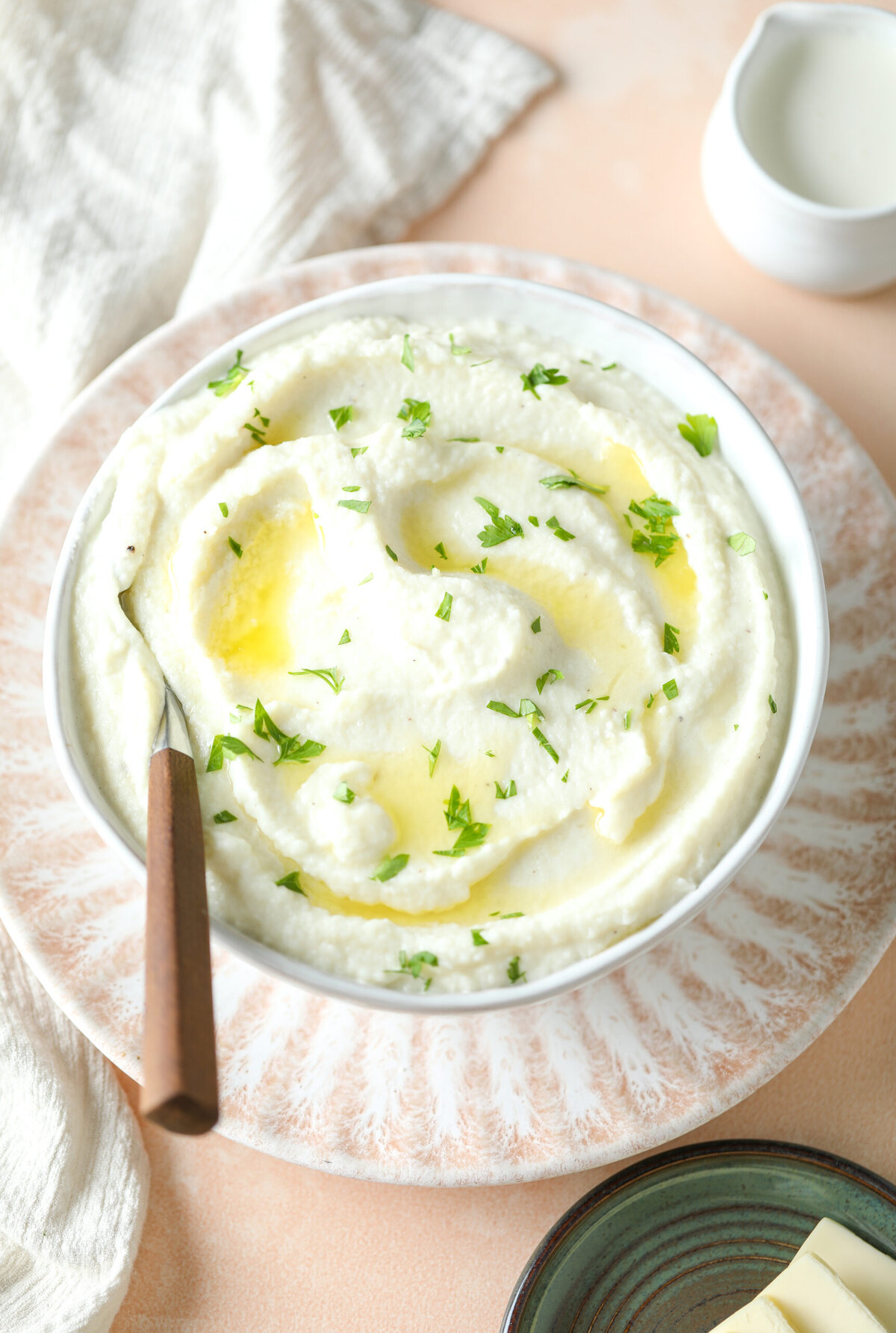 Keto cauliflower mash in a serving bowl, topped with melted butter and parsley