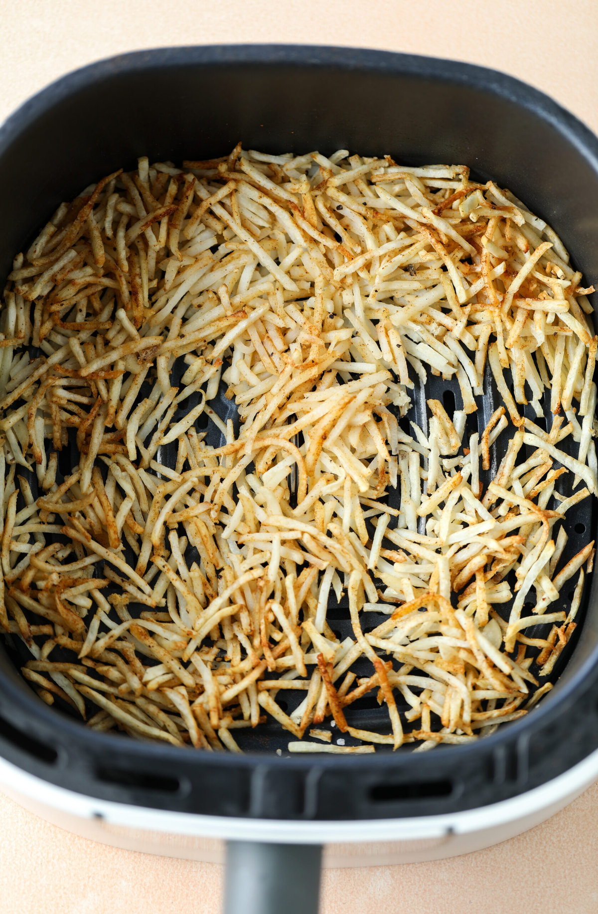 Cooked and crispy shredded hash browns in the air fryer basket