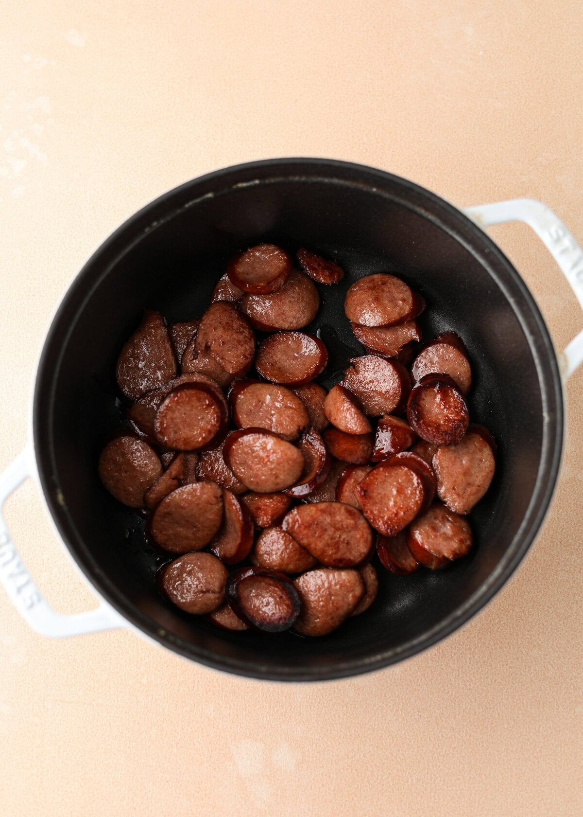 overhead shot of sautéed kielbasa in a white dutch oven